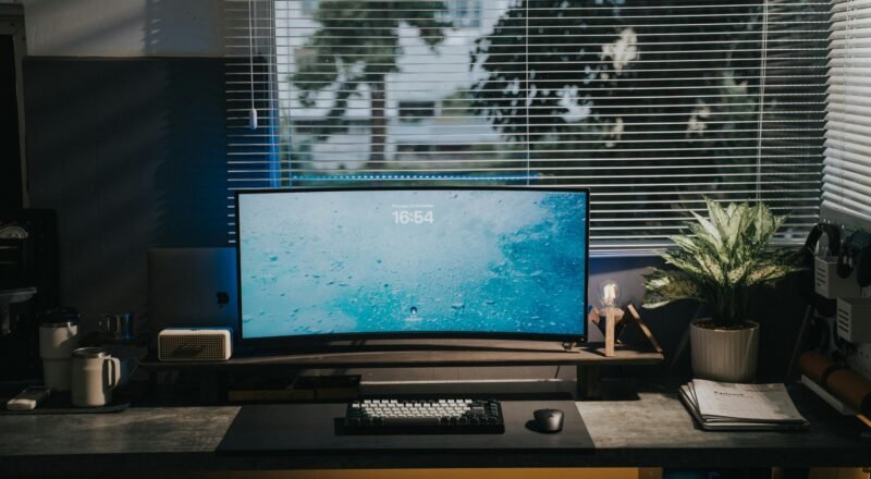 A stylish home office setup with a computer monitor, keyboard, mouse, and plant on a desk.