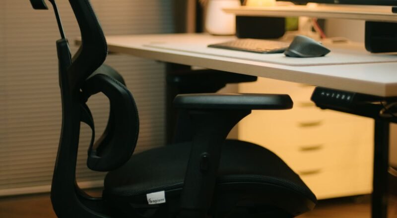 Ergonomic office chair in a cozy workspace with a desktop setup and warm lighting.