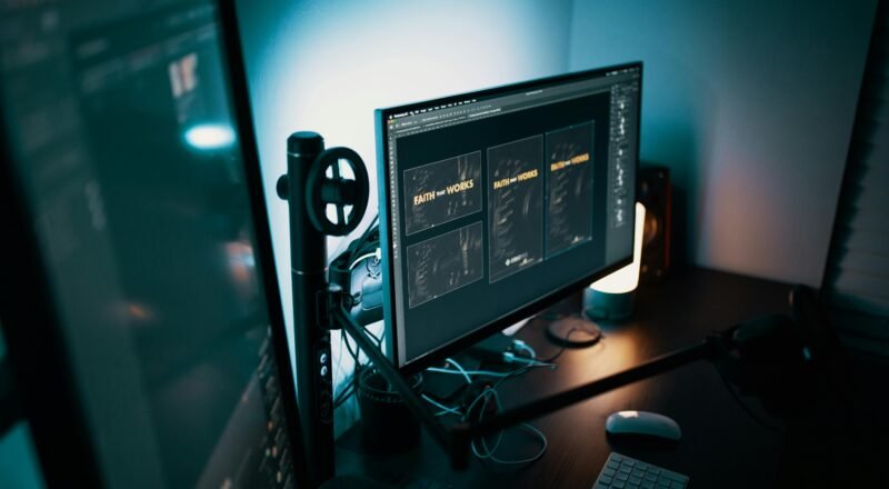 A stylish modern workspace with dual monitors displaying design software in a dimly lit room.